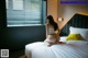 A woman sitting on a bed in a hotel room.