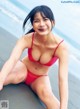 A woman in a red bikini sitting on the beach.