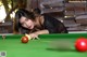 A woman leaning over a pool table with red balls.