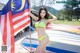 A woman in a green bikini holding a malaysian flag.