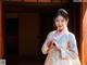 A woman in a white and pink hanbok standing in front of a door.