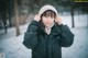 A woman wearing a black jacket and a white hat in the snow.