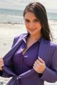 A woman in a purple suit posing on the beach.