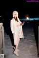 A woman in a white coat holding a sparkler in the snow.