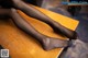 A woman's legs in black stockings sitting on a table.