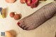 A woman in fishnet stockings standing next to a bunch of fruit.