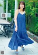 A woman in a blue dress standing on a patio.