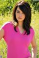 A woman in a pink shirt standing in a field.