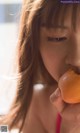 A young woman eating a donut in front of a window.