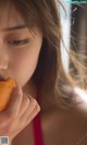 A woman in a red bikini eating a donut.