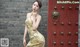 A woman in a yellow dress standing in front of a red door.