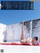 A woman in a white bikini laying on a red mat.