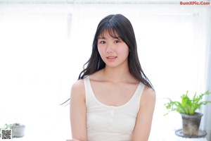 A woman in a white tank top posing for a picture.