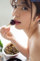 A woman eating a piece of food with chopsticks.